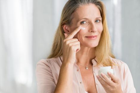 Smiling senior woman applying anti-aging cream.
