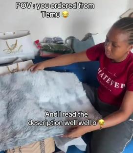 Person unboxing a small, thin, light blue rug that is much smaller than expected.