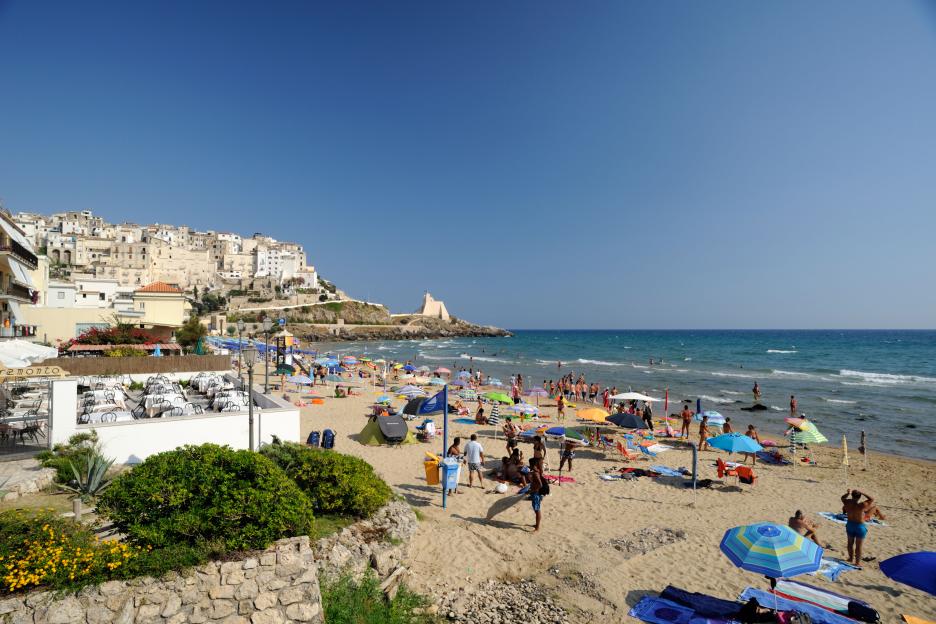 Sperlonga beach in Lazio, Italy, crowded with people and umbrellas.