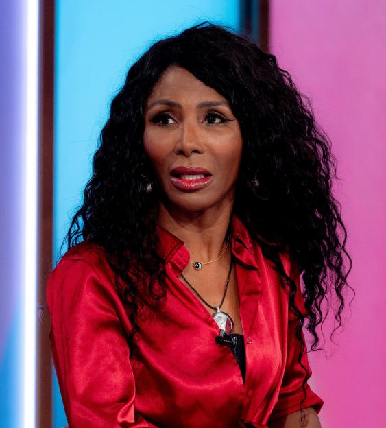 Sinitta wearing a red satin shirt and a necklace.