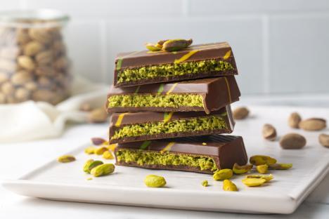 Stack of milk chocolate bars filled with pistachio paste.