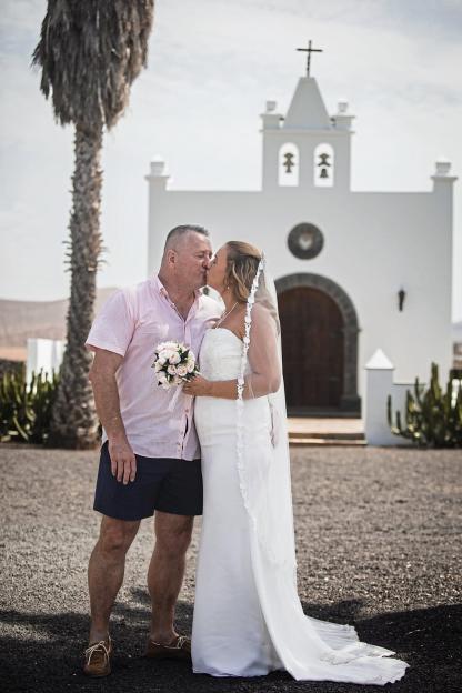 A bride and groom kissing in front of a church.