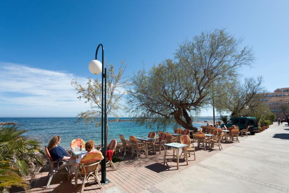 Seafront café in Cala Bona, Mallorca, where people are seated at tables overlooking the ocean.