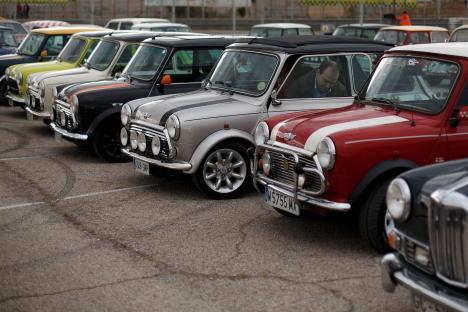 Man exiting a classic Mini Cooper at a car show.