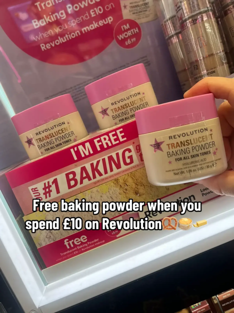 A hand holding Revolution Translucent Baking Powder, with two other containers behind it, advertising a free baking powder with a £10 Revolution makeup purchase.