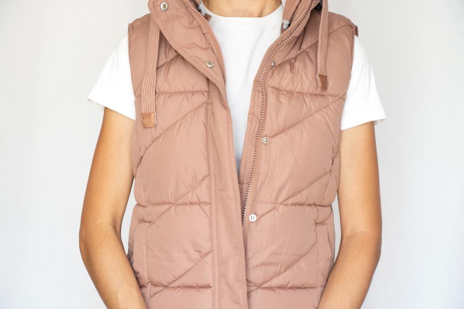 Woman wearing a pink vest over a white t-shirt.