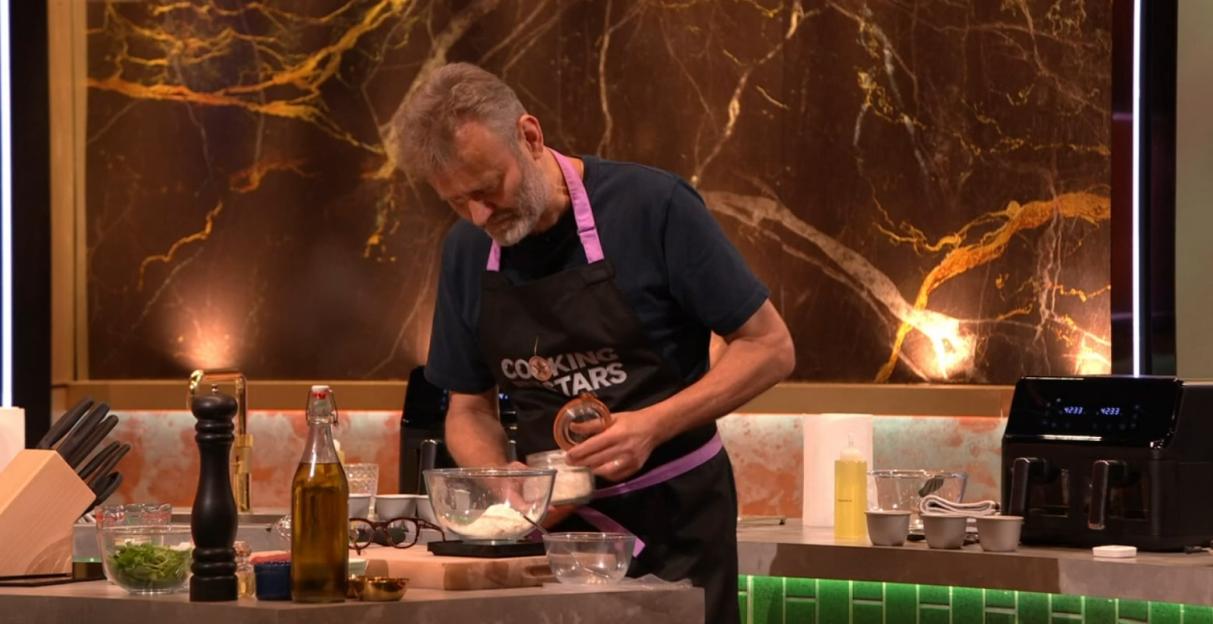 A man wearing a "Cooking Stars" apron adds flour to a bowl.