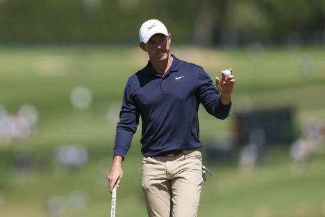 Rory McIlroy holding a golf ball on a golf course.