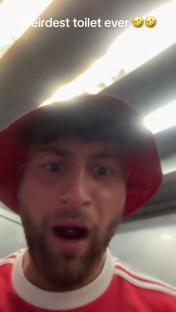 A surprised Manchester United fan in a restroom.