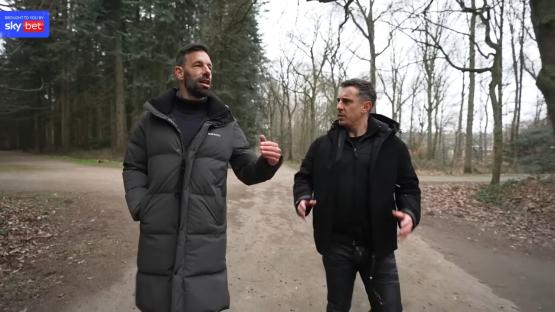 Ruud van Nistelrooy and Gary Neville walking and talking in a forest.