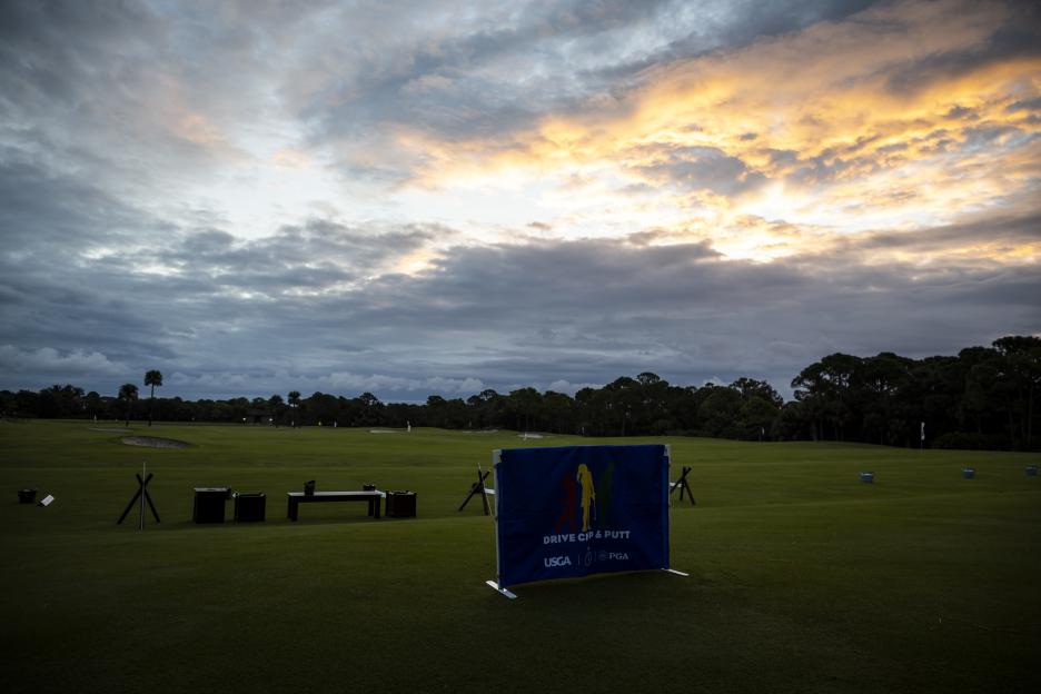 Driving range at sunset with a "Drive, Chip & Putt" banner in the foreground.