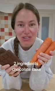 Woman holding chocolate and carrots, showing ingredients for a two-ingredient chocolate cake.