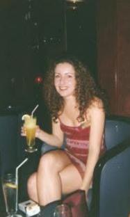 Photo of a woman in a red dress holding a cocktail.