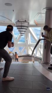 Passengers on a cruise ship taking photos of large waves through the ship's windows.