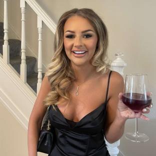 Woman in black dress holding a glass of wine.