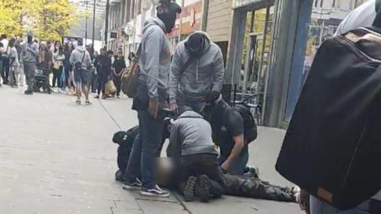 Several people restraining a person on the ground.