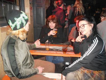 Three young adults sitting at a table in a bar, drinking.