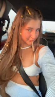 Woman in a car holding a joint.