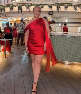 a woman in a red dress stands in front of a building