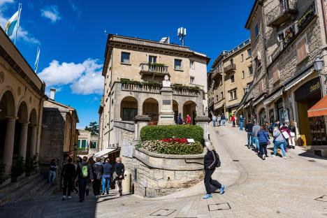 Tourists walking on a cobblestone street in San Marino's historic center, a UNESCO World Heritage Site.