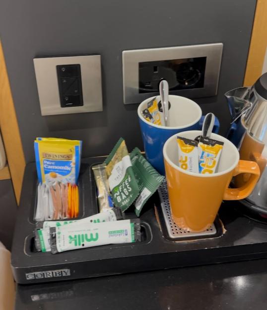 A black tray with a Corby logo holds tea, coffee, milk, sugar, and two mugs next to a kettle.