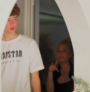 Screenshot of a young man and woman in a doorway.