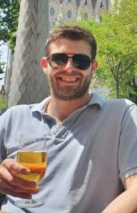 Man holding a beer in front of Sagrada Familia.