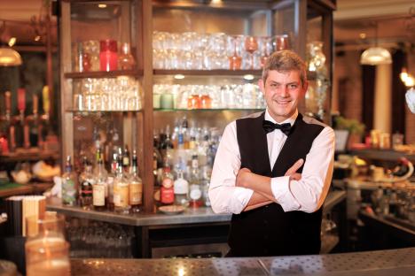 Merlin Griffiths, bartender, arms crossed.