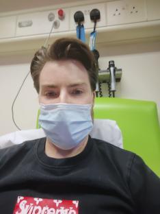 Man in hospital bed wearing a face mask.