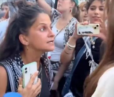 A woman angrily confronts a group of people.