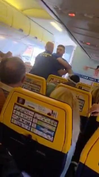 Police officers removing disruptive passengers from a Ryanair plane.