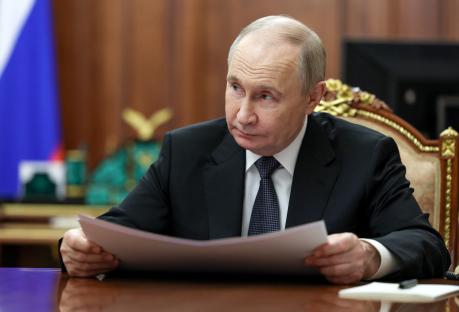 Vladimir Putin reviewing documents at a meeting.