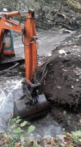 Hitachi excavator digging in a muddy stream.