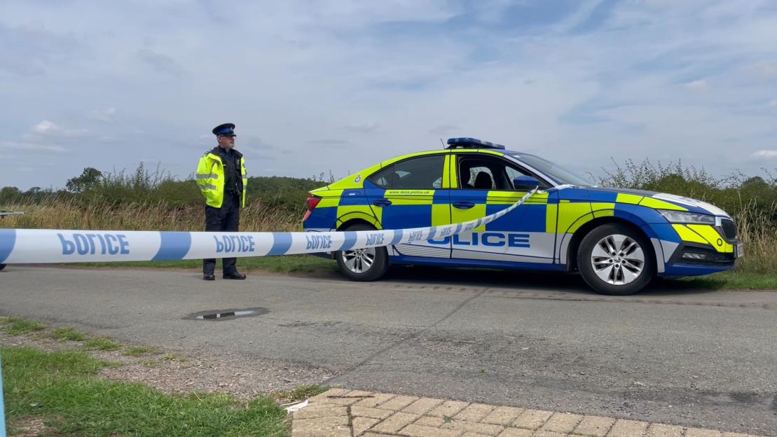 Police car and officer at scene of poisoning incident.