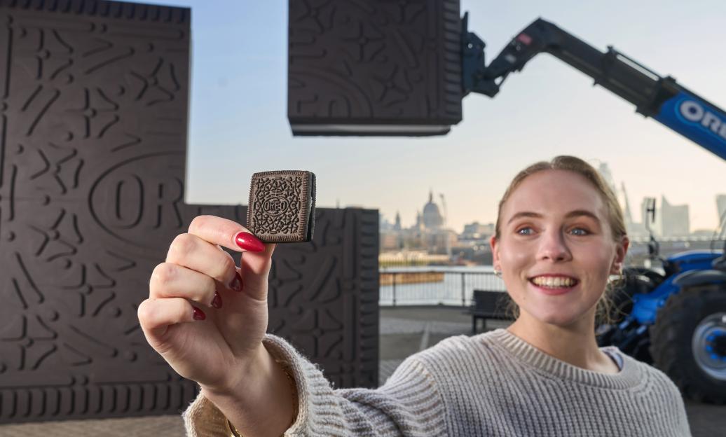 Woman holding a square Oreo cookie in front of giant square Oreo cookie sculptures.