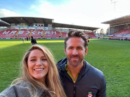 Ryan Reynolds and a Wrexham AFC player holding a trophy after the team's promotion.