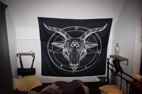 A black tapestry depicting a goat's head inside a pentagram.
