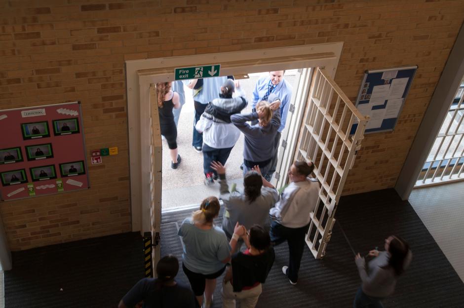 Female prisoners move through a doorway with a male prison guard.