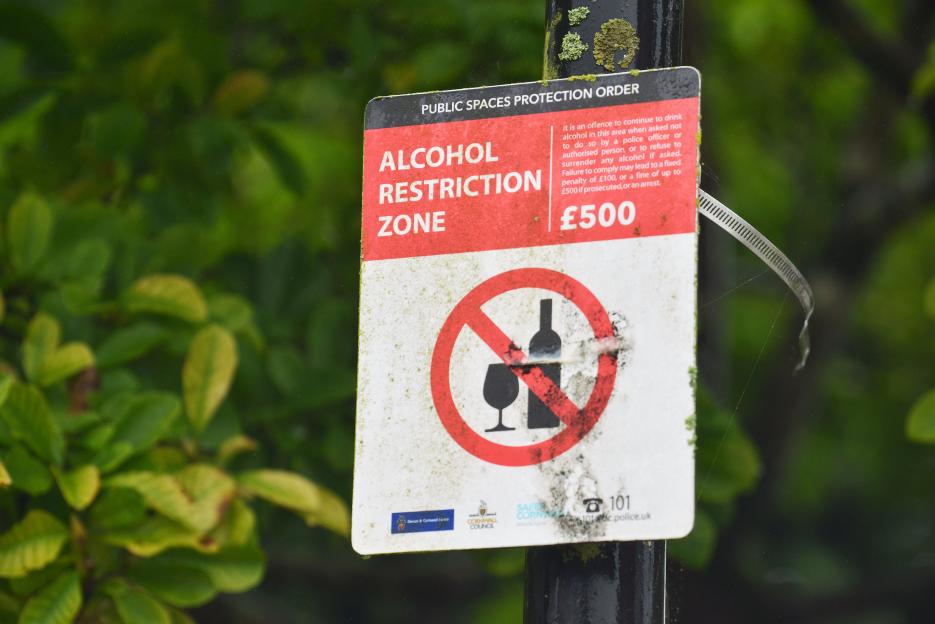 An "Alcohol Restriction Zone" sign with a £500 fine notice, prohibiting public drinking.