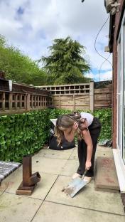 Woman cleaning patio with shovel.
