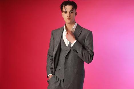 Man in gray suit against pink background.