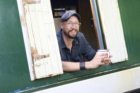 Man holding a mug, looking out a window.