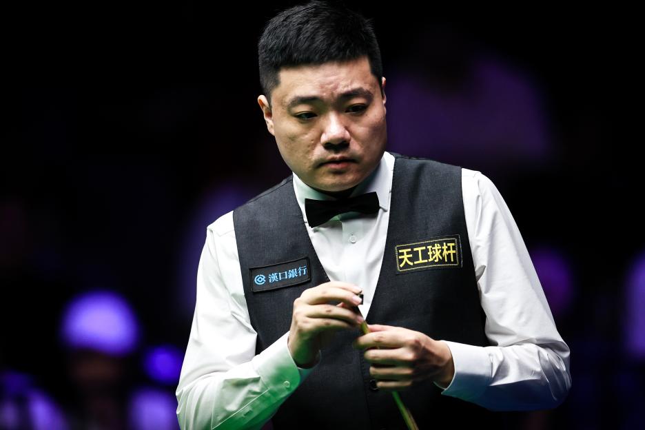 Ding Junhui chalking his cue.