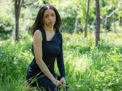 Woman kneeling in a grassy area.