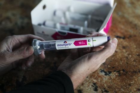 A person holding a Mounjaro injection pen.