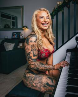 Woman with extensive tattoos playing piano.
