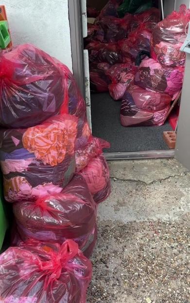 Many bags of clothing outside a doorway.