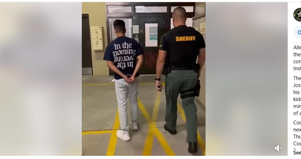 A handcuffed young man being escorted by a sheriff.