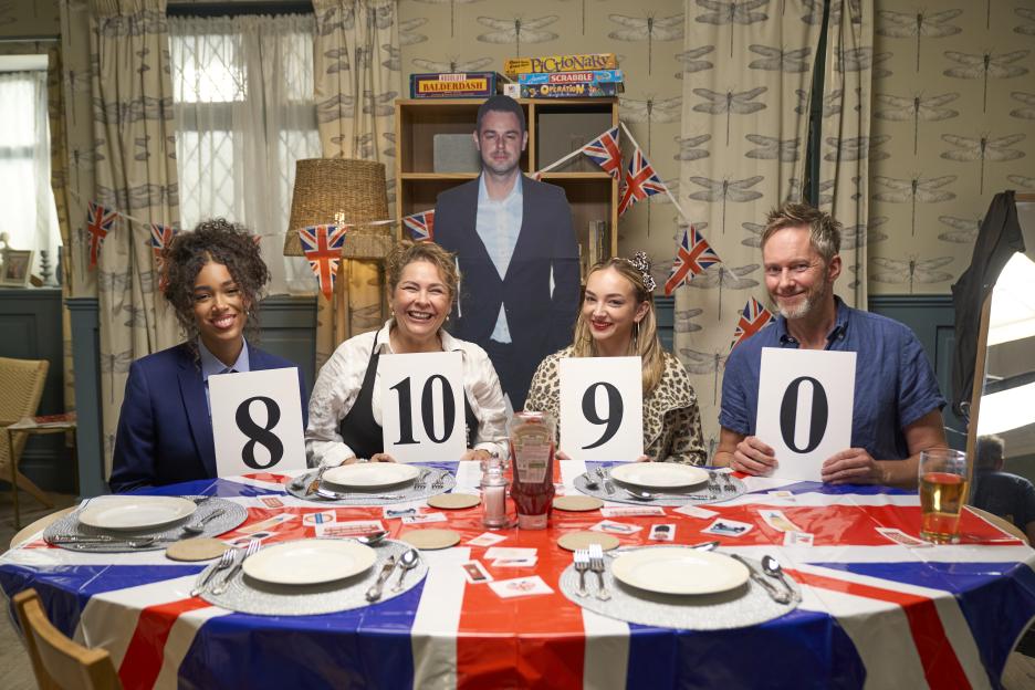 Anya Lawrence, Nicole Barber Lane, Isabelle Smith and James Redmond hold up scorecards at a table with a Union Jack tablecloth.