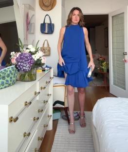 Woman in blue dress realizing one leg is tanner than the other.